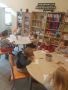 Przedszkolaki z grupy „Słoneczka” siedzące przy stolikach i wykonujące zadania plastyczne.