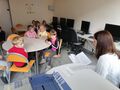 Dzieci słuchają czytanego im opowiadania przez nauczyciela bibliotekarza.
