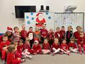 Dzieci z grupy Gwiazdeczek wraz z Paniami pozują do zdjęcia na tle obrazka ze Świętym Mikołajem