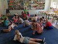 Dzieci leżąc na dywanie słuchaja opowiadania o słoniu w kratkę