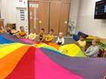 Dzieci z grupy Giwazdeczek machają kolorową chustą z materiału