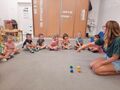Dzieci siedzą na dywanie z nauczycielem