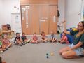 Dzieci siedzą w kole. Nauczyciel pokazuje pomarańczową piłeczkę