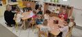 Dzieci z grupy Gwiazdeczki siedzące przy dwoch stolikch z nauczycielem