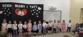 Dzieci z grupy Gwiazdeczek stoją na tle dekoracji z okazji Dnia Mamy i Taty