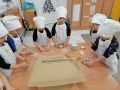 Dzieci z grupy Gwiazdeczki ubrane w stroje kucharskie gnota ciasto na pierniki