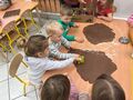 Dzieci z grupy Gwiazdeczek siedzą przy stoliku i wykrawają gotowymi formami ciastka