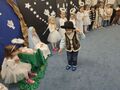 Chłopiec w roli Króla stoi na dywanie przy żłóbku Maryi i aniołkach