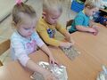 Przedszkolaki wkładają mieszankę zbóż do foremek