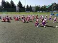 Dzieci ubrane w fioletowe i czerwone koszulki siedzace na boiskujpg