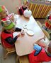 Czworo dzieci siedzi przy stoliku i maluje dynie farbami na biało