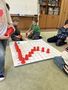 Dzieci z grupy Promyczków układają z czerwonych platikowych kubków literę