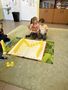 Dziewczynka i chłopiec z grupy Promyczków sprawdzają czy dobrze ułożyli z plastikowych kubków literę Wjpeg
