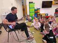 Dzieci słuchają piosenki granej na gitarze