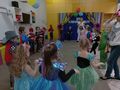 Dzieci w strojach karnawałowych tańczą w kole do muzyki