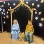 Chłopiec i dziewczynka grajacy role św.Józefa i Maryji siedzą na tle dekoracji do przedstawienia z okazji dnia babci i dziadka