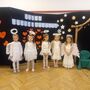 Pięcdziewczynek przebranych za aniołki stoją na tle dekoracji do przedstawienia na dzień babci i dziadka