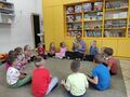 dzieci z grupy sloneczka siedzą na dywanie i sluchaja czytanej przez nauczycielke ksiązki