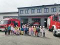 Dzieci i strazacy stoja przed remiza OSP w Turosni Koscielnej